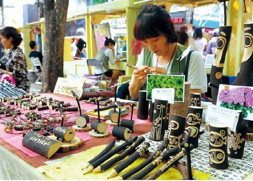 Asirang carves patterns on her wooden accessories at Hongdae Hope Market, which opens every Sunday. Lee Sang-sub/The Korea Herald