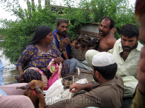 People insist on bringing their animals, including chickens and a goat, as they are rescued by the Pakistan navy. (MCT-Yonhap)
