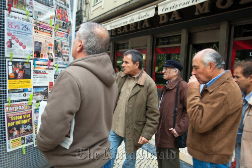 Pedestrians read the news headlines at a newspaper stand in Lisbon. (Bloomberg)