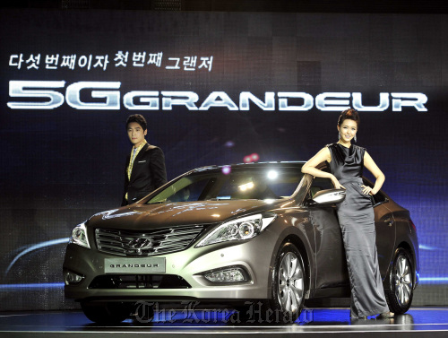 Models pose with the latest version of Hyundai Motor Co.’s large sedan Grandeur launched on the local market Thursday. The fifth generation Grandeur is available with 3- or 2.4-liter gasoline direct injection engines. (Hyundai Motor Co.)