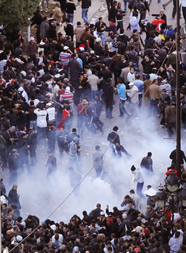 Demonstrators run as police throw tear gas during a demonstration in Tunis on Friday. (AP-Yonhap News)