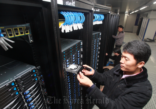 Workers check server computers at a data center in Seoul. (The Korea Herald)