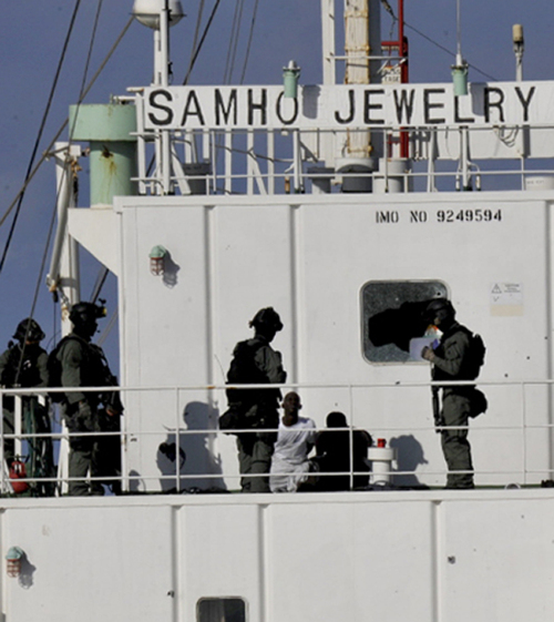 Korean naval special forces keep watch on Somali pirates they subdued in a military operation aboard the hijacked Korean-operated Samho Jewerly freighter ship in the Indian Ocean on Friday. (Navy)