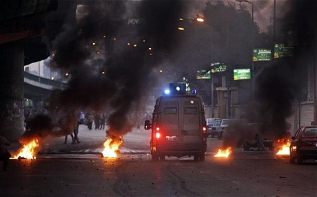 A riot van drives through a burning barricade in Cairo. (AP)