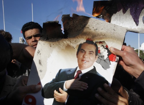 Protestors burn a photo of former Tunisian President Zine El Abidine Ben Ali during a demonstration in Tunis against holdovers from Ben Ali’s regime in the interim government. (AP-Yonhap News)