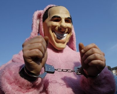 A demonstrator wears a mock mask of Italian Premier Silvio Berlusconi, dressed as a pink rabbit with handcuffs during a protest outside Berlusconi's private residence, in Arcore, Italy, Sunday, Feb. 6, 2011, to demand Premier Silvio Berlusconi's resignation following allegations he paid for sex with a 17-year-old girl and used his office to cover it up. (AP Photo/Luca Bruno)