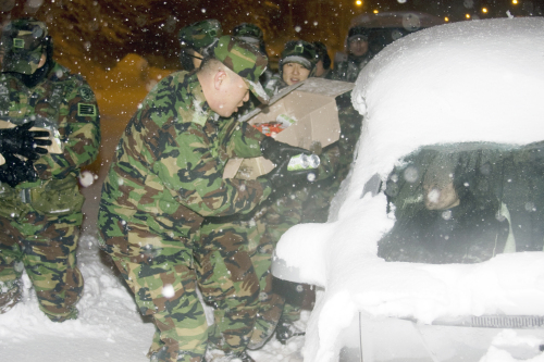 A soldier hands over sodas to a motorist stranded on a highway due to heavy snowfall on the east coast Saturday. (Yonhap News)