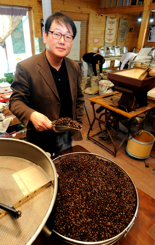 Coffee Cupper owner Kim Jun-young scoops up roasted beans. (Photo: Coffee Cupper)