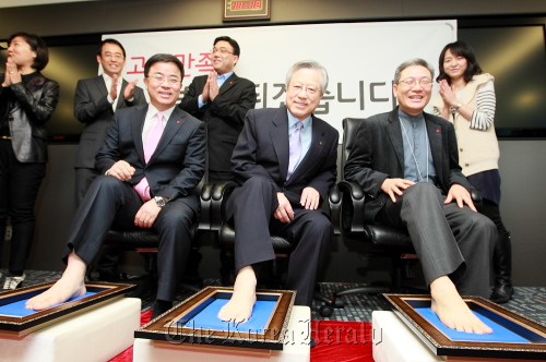 KT’s executives make foot imprints as they pledge to improve customer service at an event held at the Olleh Campus in southern Seoul on Monday. From left are Pyo Hyun-myung, president of KT’s mobile business group, KT chairman Lee Suk-chae and Seo Yu-yeol, president of the home customer group at KT. (KT Corp.)