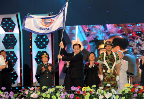 Mungyeong Mayor Shin Hyun-kook waves a flag hoping for the city’s successful bid for the CISM Military World Games 2015 during a local riverside festival last August. (Mungyeong City)