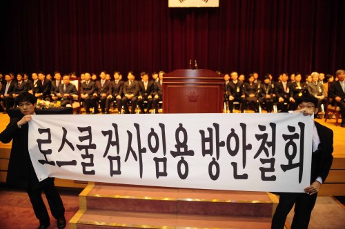 Members of a new class at the Judicial Research & Training Institute hold a placard against the government's policy to give priority to law school graduates in appointing prosecutors on Wednesday. (Park Hae-mook/The Korea Herald)