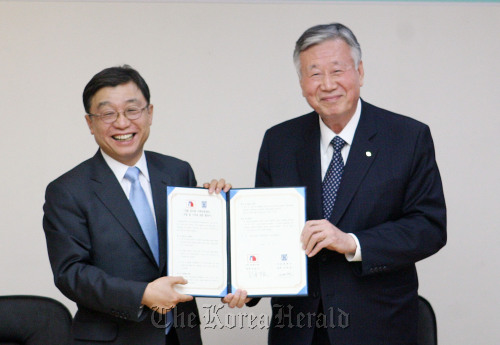 Seoul National University President Oh Yeon-cheon (left) and Booyoung Group Chairman Lee Joong-keun after Lee signed a pledge of donation for the construction of a social contribution center on the campus Wednesday. (Yonhap News)
