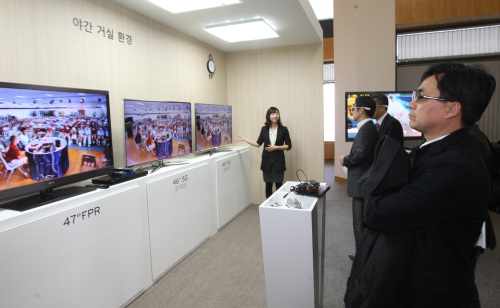 Reporters compare 3-D televisions from Samsung Electronics and LG Electronics at a demonstration event hosted by LG Display at its headquarters in Seoul on Thursday. (Yonhap News)