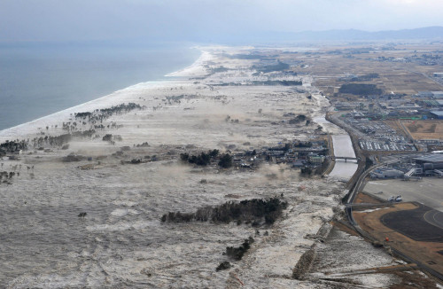 Earthquake-triggered tsumanis sweep shores along Iwanuma in northern Japan on Friday March 11, 2022. The magnitude 8.9 earthquake slammed Japan's eastern coast Friday, unleashing a 13-foot (4-meter) tsunami that swept boats, cars, buildings and tons of debris miles inland. (AP-Yonhap News)