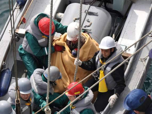 Japanese Hiromitsu Shinkawa, wrapped in a blanket, is lifted to a Maritime Self-Defense Force destroyer following his rescue on Sunday March 13, 2011. (AP-Yonhap News)