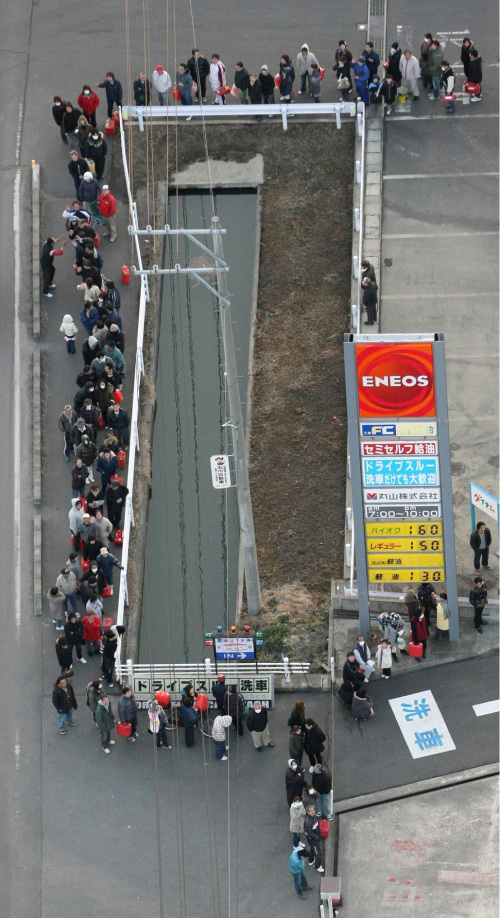 People queue up around a ditch to buy kerosene at a gas station in Watari, Miyagi Prefecture. (AP-Yonhap News)