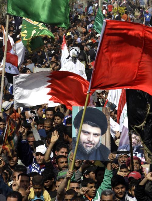Iraqi Shiite Muslims hold the Bahraini flag and an image of Shiite radical leader Moqtada Sadr as they protest in Sadr City in eastern Baghdad on Wednesday, in support of Shiite protesters in Bahrain and against the violent crackdown by the ruling Sunni Muslim dynasty in the Bahraini capital Manama. (AFP-Yonhap News)