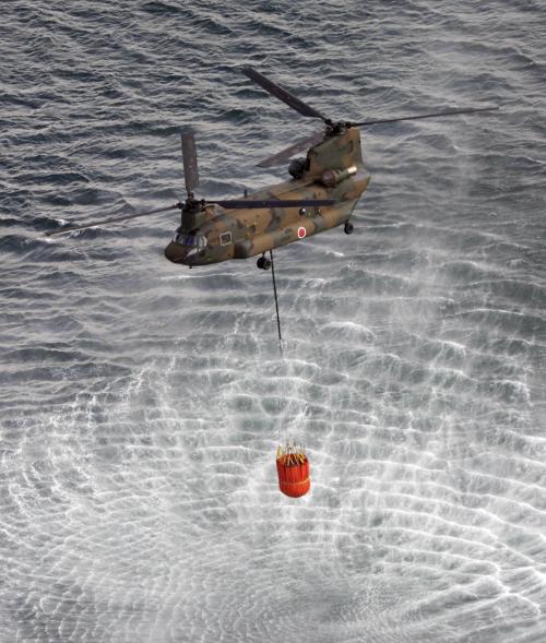 A Japan Self-Defense Forces helicopter scoops water off Japan’s northeast coast on its way to the Fukushima Daiichi nuclear power plant in Okumamachi on Thursday. (AP-Yonhap News)
