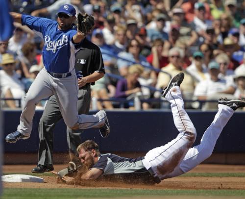 Kansas City Royals third baseman Pedro Feliz leaps for a wide throw as Seattle Mariners’ Michael Saunders steals third during the third inning of a spring training baseball game in Peoria, Arizona, Thursday. (AP-Yonhap News)