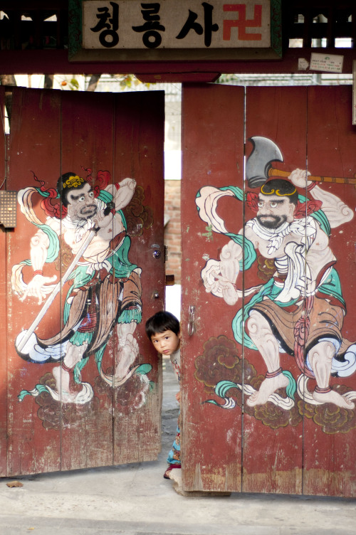 A boy peeks out of the entrance to Cheongryeong Temple near Singil Station.