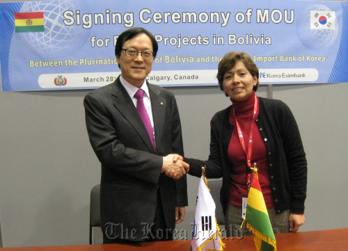 Kim Yong-hwan (left), chairman and president of the Export-Import Bank of Korea, shakes hands with Viviana Elba Caro Hinojosa, minister of development planning of Bolivia, after signing a contract on the Economic Development Cooperation Fund totaling $50 million in Calgary on Tuesday. (Export-Import Bank of Korea)