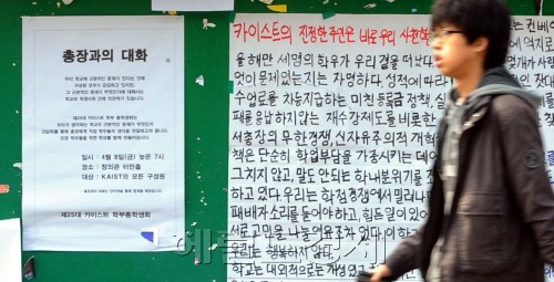 (A student in the KAIST campus in Daejeon walks past a hand-written poster protesting the school president’s policies that stir competition, including a unique system under which students pay different amounts of tuition based on their grades. Park Hyun-koo/The Korea Herald)