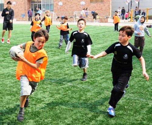 Kids enjoy a game of touch with Han River Pirates at Dulwich College Seoul. (Shane Lowndes)