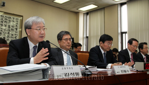 Financial Services Commission Chairman Kim Seok-dong (left) responds to a question from lawmakers at a parliamentary hearing on the closure of several savings banks Thursday. (Yonhap News)