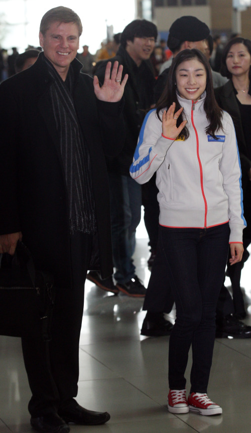 Figure skating champion Kim Yu-na and her American coach Peter Oppegard wave to the crowd at Incheon International Airport on Friday. (Yonhap News)