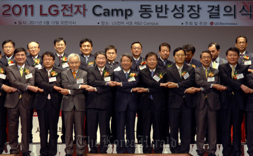 LG Electronics vice chairman Koo Bon-joon (fourth from left, front row), Chung Un-chan, head of the Presidential Commission on Shared Growth for Large and Small Companies (fifth from left, front row), and LG’s subcontractors pledge mutual growth at the company’s research and development center in southern Seoul on Thursday. (LG Electronics)