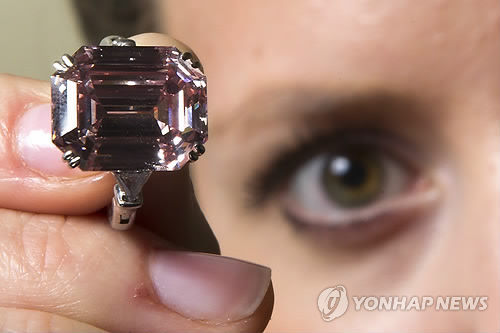 A model holds up a ring mounting a rare translucent pink diamond during a Sotheby's auction press preview in Geneva. Mounted in a ring the 10.99-carat, emerald-cut stone that is classified as 