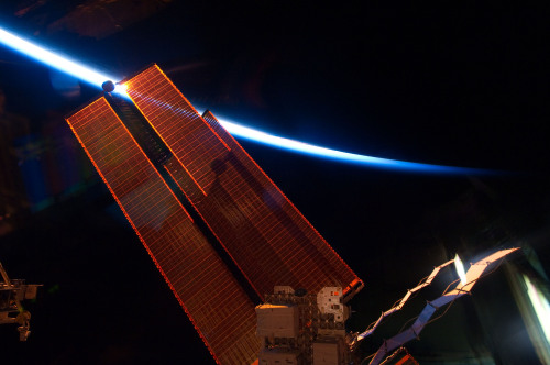 This image provided by NASA shows the intersecting thin line of Earth's atmosphere with the International Space Station's solar array wings photographed Thursday May 20, 2011 by an STS-134 crew member while space shuttle Endeavour remains docked with the station. (AP-Yonhap News/NASA)