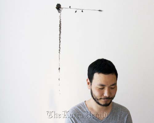 Ham Jin stands under one of his works at PKM Gallery in Hwa-dong, central Seoul. (PKM Gallery)