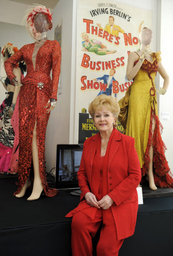 In this June 10, 2011 photo, entertainer Debbie Reynolds poses between dresses worn by actress Marilyn Monroe in the films 