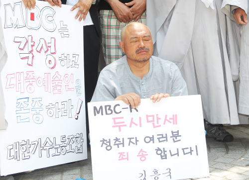Singer Kim Heung-guk has his head shaved in front of the MBC head office in Seoul on Friday, protesting the broadcaster’s decision to dismiss him from a radio program. (Yonhap News)