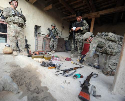 U.S. soldiers examine confiscated ammunition and guns inside a house during a raid in Afghanistan on Sunday. (AFP-Yonhap News)
