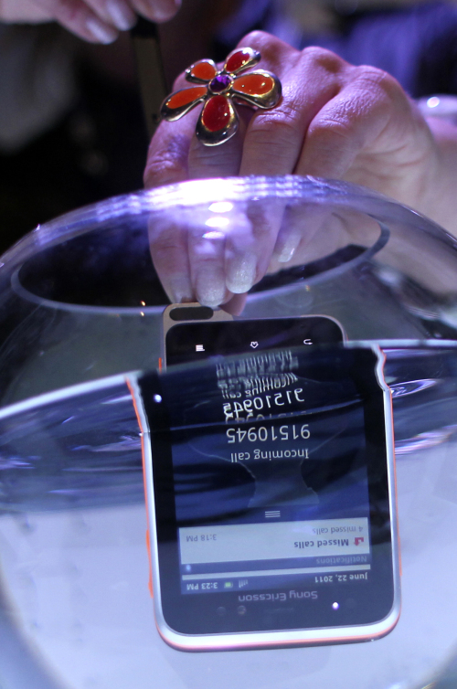 A staff member submerges the Xperia Active in a bowl of water, to show its underwater capability in Singapore on Wednesday. (AP-Yonhap News)