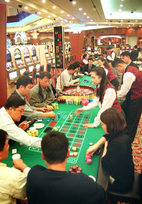 Casino gamblers sit around a gaming table. The government is seeking to allow more casinos to admit Korean nationals. (The Korea Herald)