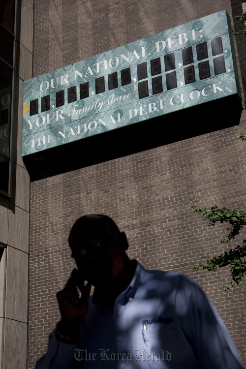 A pedestrian walks past “The National Debt Clock,” displayed on the side of a building near an Internal Revenue Service office in New York. (Bloomberg)