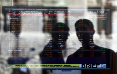 A man looking a stock exchange board monitor is reflected in the window of a bank in Milan on Monday. (AP-Yonhap News)