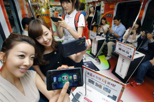 Models show LG Optimus 3-D smartphones in an “on-board” advertising campaign on Seoul’s Subway Line No. 2, Monday. (LGE)