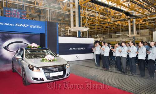 Renault Samsung Motor Co. executives and workers applaud at a ceremony to mark the start of production of the new SM7 sedan at a factory in Busan on Monday. (Yonhap News)