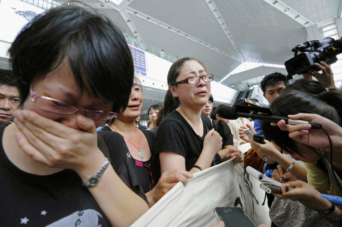 Relatives of the victims in Saturday's train crash talk to the media as they hold a banner demanding pursuit of truth of the accident during a protest at Wenzhou South Railway Station in Wenzhou, east China's Zhejiang Province, Wednesday, July 27, 2011.  (AP-Yonhap News)
