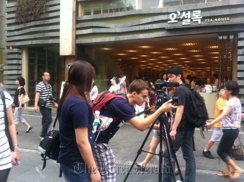 Harvard University student Nic Galat adjusts his camera while filming in the streets of Seoul. (Harvard Korea Institute)