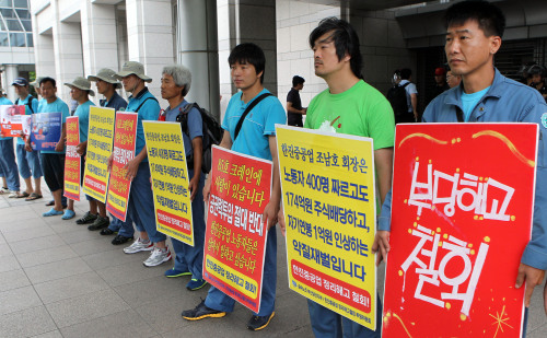 Members of the Korean Confederation of Trade Unions hold placards urging Hanjin Heavy Industries & Construction to rescind its massive layoffs in front of Busan City Hall, Wednesday. (Yonhap News)