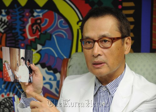To Shin-woo shows a photo of Andre Kim and himself taken in 2006 in Cambodia when Kim held the first-ever fashion show at Angkor Wat. (Lee Sang-sub/The Korea Herald)