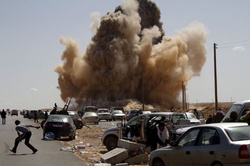 Libyan rebels take cover as a bomb dropped by an air force fighter jet explodes. (AFP-Yonhap News)