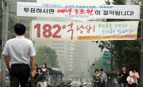 Two banners showing opposite views on the upcoming plebiscite on free school meals hang over a street in Jongno, Seoul, on Tuesday. One urges citizens to participate in the vote, while the other calls it a waste of tax payers’ money. (Park Hae-mook/The Korea Herald)