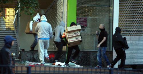 Looters run from a store in Birmingham last Tuesday during riots that left five dead, and thousands arrested. (AP-Yonhap News)