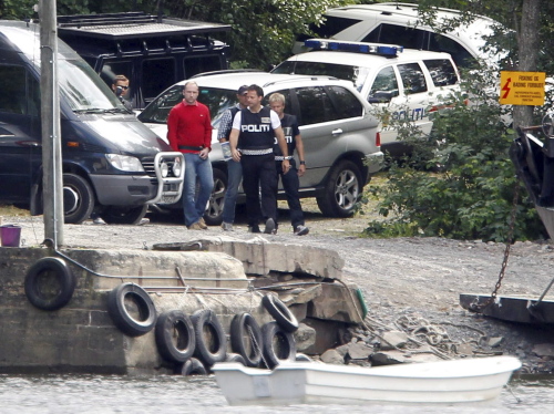 Anders Behring Breivik , center left with red jumper, is led by police to the quayside to be taken by boat back to nearby Utoya island in central Norway. (AP-Yonhap News)